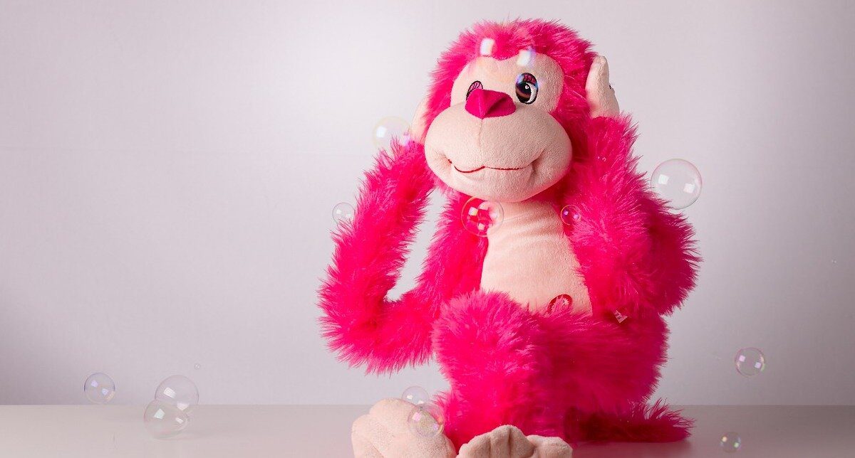A plush, hot pink toy covering its ears